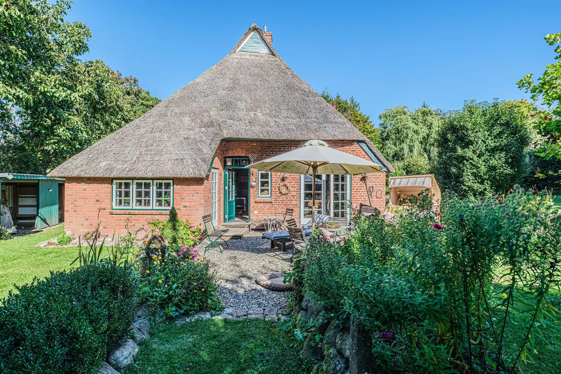 Reetdachhaus in Sierksdorf mit blühendem Garten, fotografiert für die Vermarktung durch Freesia Immobilien
