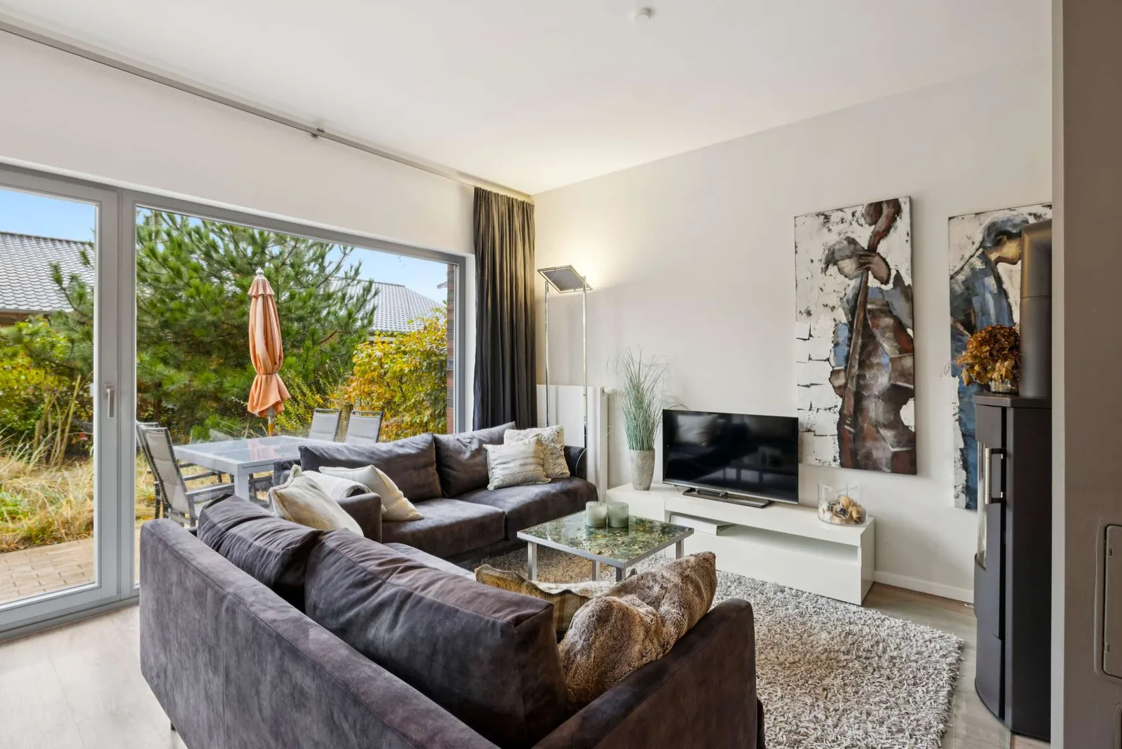 Wohnzimmer mit großer Fensterfront und Blick ins Grüne