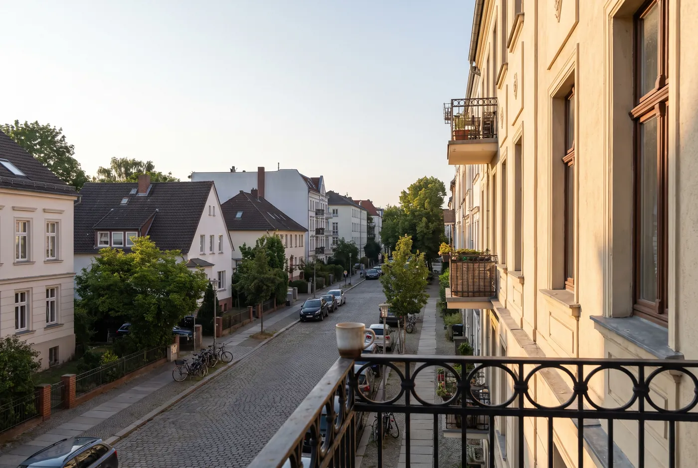 Blick vom Balkon einer Stadtwohnung auf eine Wohnstraße am Morgen