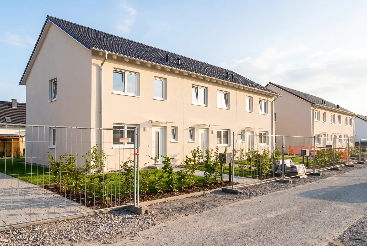Neu gebaute Reihenhäuser mit hellen Fassaden und Vorgärten